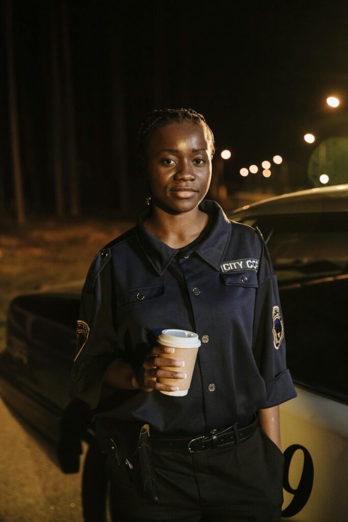 African American policewoman enjoys a coffee break at night.